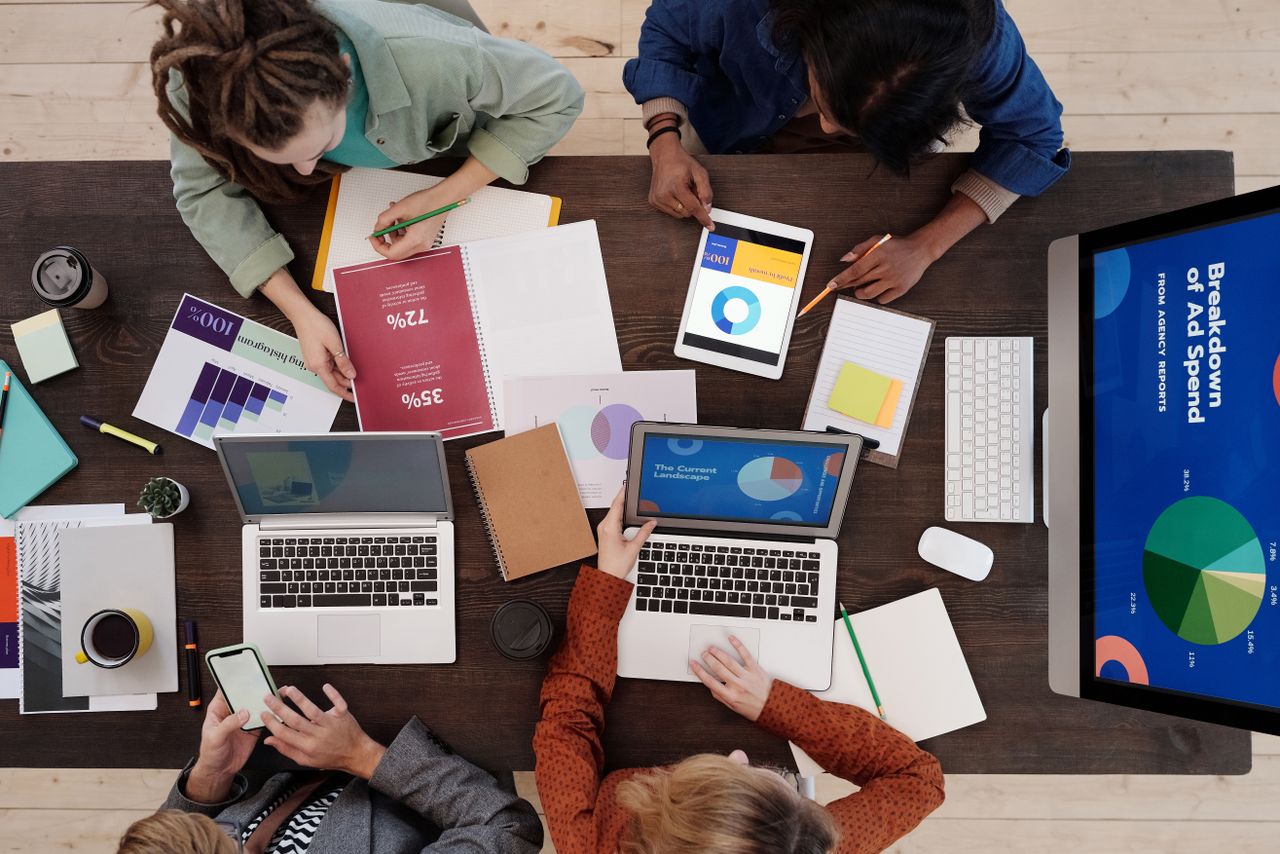 A diverse team working together on digital marketing strategies around a desk, using laptops and tablets.